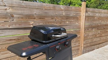 A black outdoor grill with a digital display and control knobs, placed on a metal stand.