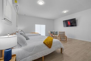 Ein Hotelzimmer mit zwei Betten, einem Fernseher, einem Schreibtisch und einem Stuhl.