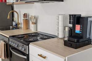 Una cocina moderna con estufa a gas, cafetera y electrodomésticos de acero inoxidable.