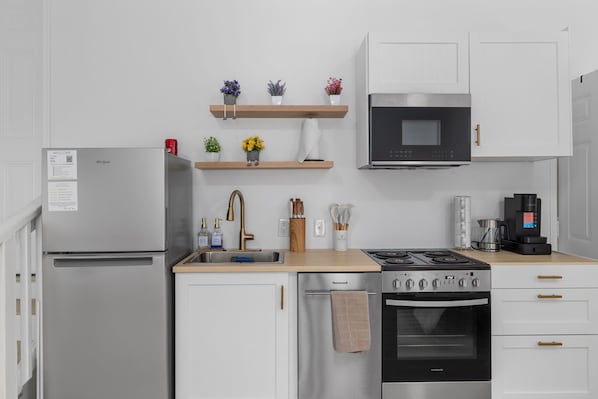 Una cocina moderna con refrigerador, estufa, horno, microondas y repisas de madera con flores.