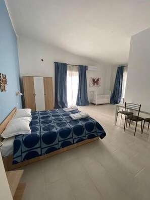Ein Schlafzimmer mit Bett, Stuhl, Schreibtisch und Heizkörper.