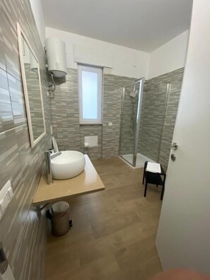 Ein Badezimmer mit einem großen Waschbecken, einer Dusche und einem Fenster.