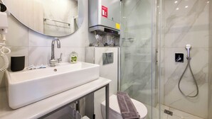 Een moderne badkamer met een wastafel, spiegel, toilet en douchecabine met glazen wanden.