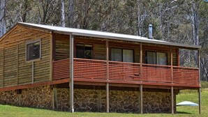 Eine Blockhütte mit Steinunterbau, einem Balkon und einem Schornstein.