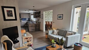 Un salon moderne avec un canapé, un téléviseur, une table basse et un panier pour animaux de compagnie.