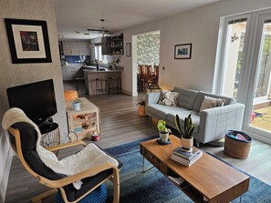Ein modernes Wohnzimmer mit einer Couch, einem Fernseher, einem Couchtisch und einem Körbchen für ein Haustier.