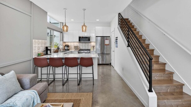 A modern kitchen with a central island, bar stools, stainless steel appliances, and pendant lighting. - Perch - Capitol Luxe B | Prime Location in Cap Hill | Walk Score 93 (Seattle)