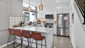 A modern kitchen with a central island, stainless steel appliances, and pendant lighting. - Perch - Capitol Luxe B | Prime Location in Cap Hill | Walk Score 93 (Seattle)