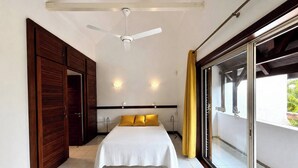 A bedroom with a bed, a ceiling fan, a sliding glass door, and a view of greenery outside. - Paradise House in Trou-aux-biches (Mont Choisy)