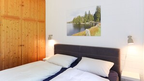 Un dormitorio con cama, pared de paneles de madera y una pintura de paisaje.