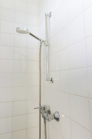 Een douche met een handdouche en een kraan aan de muur.