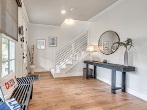 Eine Treppe mit weißen Geländern, ein Konsolentisch mit Lampe und eine Vase mit Grünpflanzen.