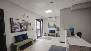 A reception area with a desk, bench, and two framed pictures on the wall. - Falkenberg Business Centre and Suites (Botwood)