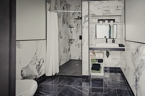 A modern bathroom with a toilet, shower, and sink area. - Falkenberg Business Centre and Suites (Botwood)