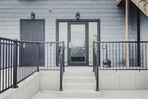 A building entrance with a concrete staircase, metal railings, and two doors.