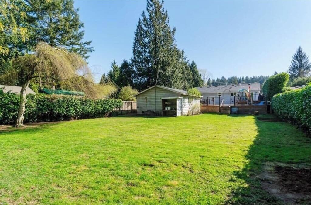 A residential property with a well-maintained lawn, a small shed, and a house with a visible garage.