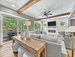A modern living room with a sectional sofa, a wooden coffee table, a fireplace, and a TV mounted on the wall. - Modern Coastal Home with Private Pool and Free Golf Cart (Hilton Head Island)