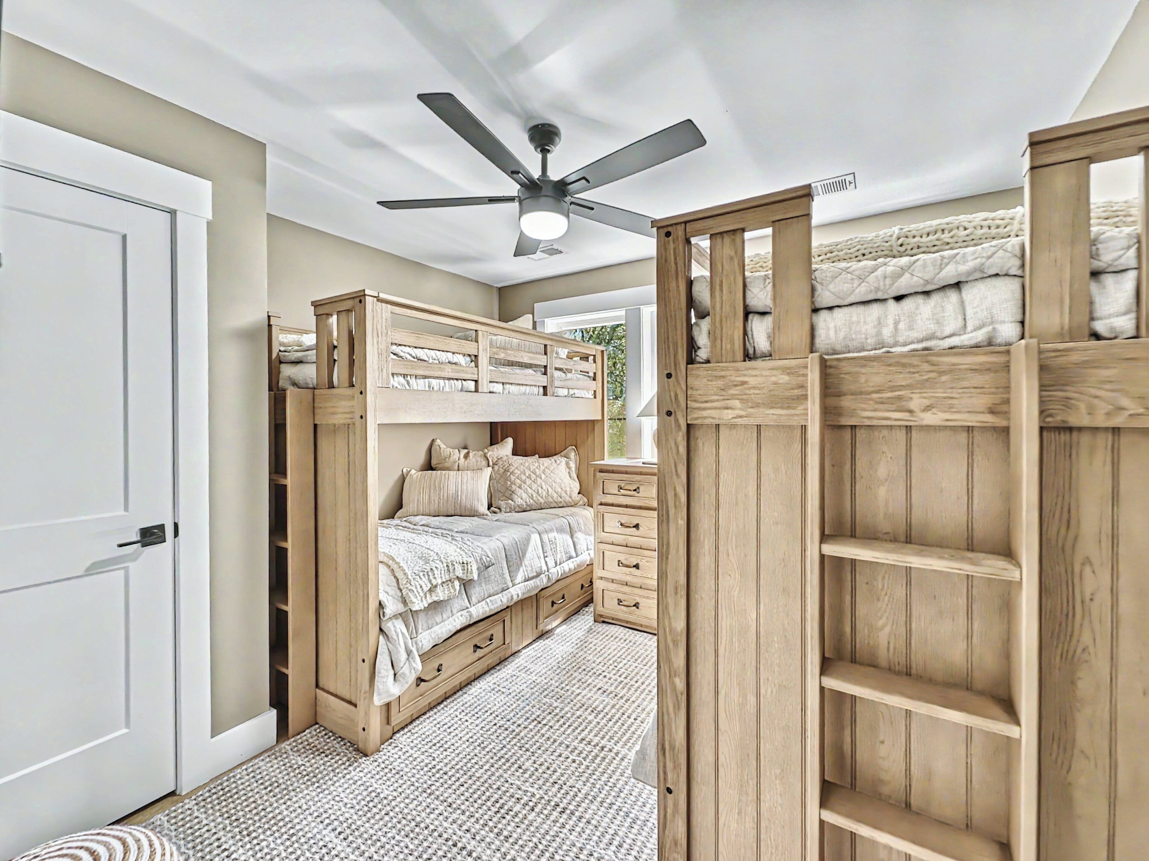 A bedroom with a bunk bed, a ceiling fan, and a wooden dresser.