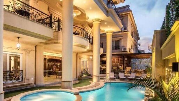 A swimming pool with a circular design, surrounded by a wooden deck and palm trees. - Maran Residence (Cairo Governorate)