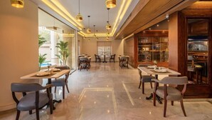 A spacious dining area with multiple tables and chairs, pendant lighting, and a view of the outdoors. - Maran Residence (Cairo Governorate)