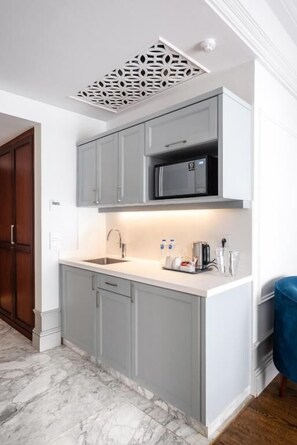 A kitchen with grey cabinets, a microwave, and a sink.
