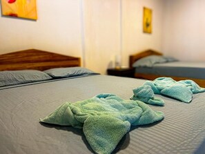 A hotel room with two beds, each with a wooden headboard, and a nightstand with a lamp. - Iguana Villas (Puerto Viejo de Talamanca)