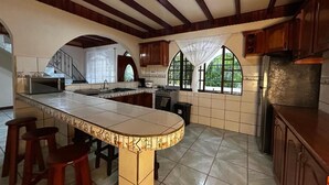A kitchen with a large island, wooden cabinets, and a view through the windows. - Iguana Villas (Puerto Viejo de Talamanca)
