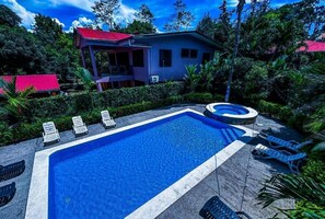 A swimming pool with lounge chairs, a hot tub, and a house with a red roof. - Iguana Villas (Puerto Viejo de Talamanca)