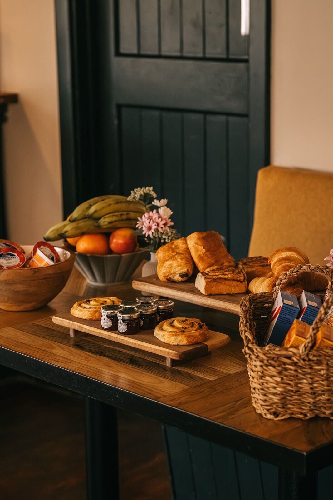 A wooden table with pastries, bread, and jars of jam.