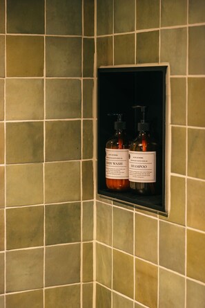 A tiled wall with a small shelf containing two bottles labeled 'BODY WASH' and 'SHAMPOO'. - Boot and Shoe (Flintham)