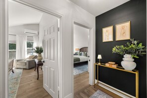 Un pasillo con pared negra, una puerta blanca y una consola con un florero y libros.