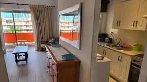 A kitchen with white cabinets, a countertop, and a stove. - Crisol (Los Cristianos)