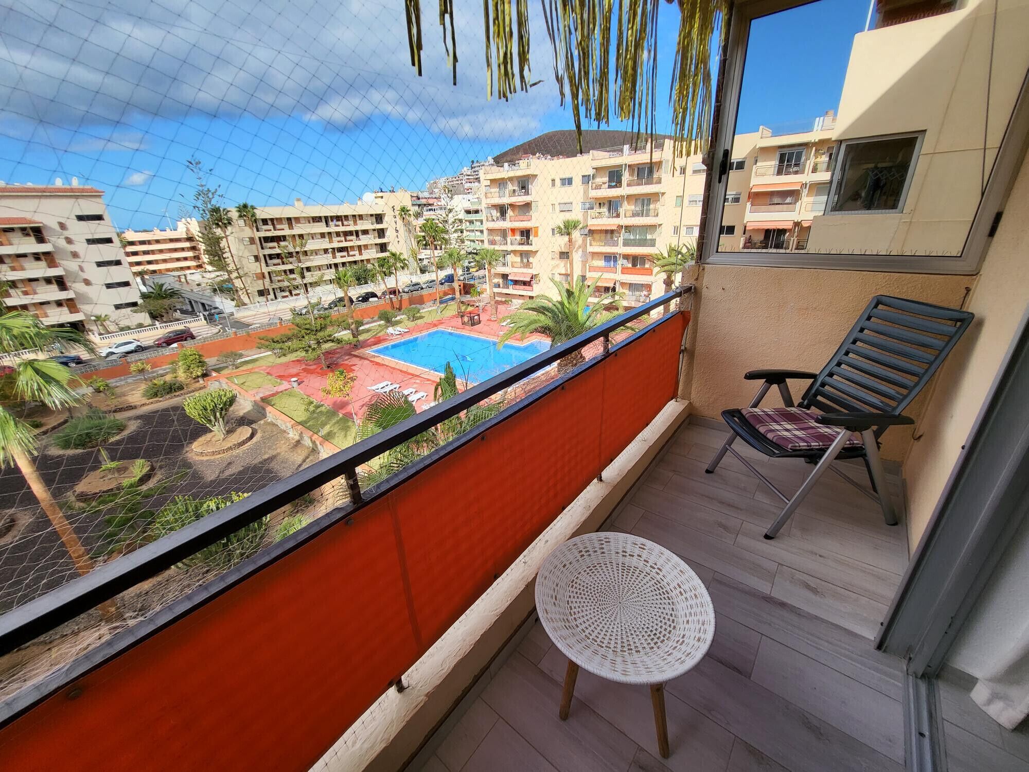 Un balcón con vista a una piscina, una silla y una pequeña mesa.
