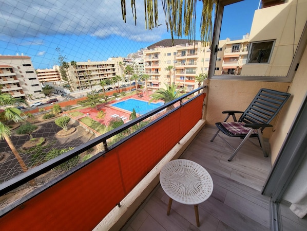 Ein Balkon mit Blick auf einen Swimmingpool, einem Stuhl und einem kleinen Tisch.