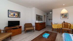A living room with a TV, sofa, dining table, chairs, and a mirror. - Crisol (Los Cristianos)