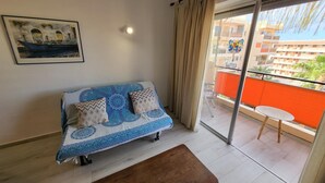 A room with a sofa, a bench, a balcony with a table, and a painting on the wall. - Crisol (Los Cristianos)