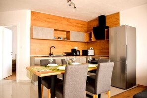 Eine moderne Küche mit Esstisch für vier Personen, einem Edelstahlkühlschrank und Holzschränken.