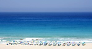 A beach with rows of umbrellas and chairs, a clear blue sky, and the ocean. - Wester Sun new Apartment Near Balos Falassarna (Kissamos)
