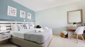 Quarto com cama, mesas de cabeceira, escrivaninha, cadeira e quadros nas paredes.