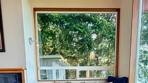 A room with a sofa, a chair, a patterned rug, and a view of trees through a window. - Luxury Bay Retreat Hot Tub Views (Bellingham)