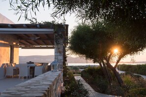 Une terrasse extérieure avec un sol en pierre, une pergola et une vue sur la mer.