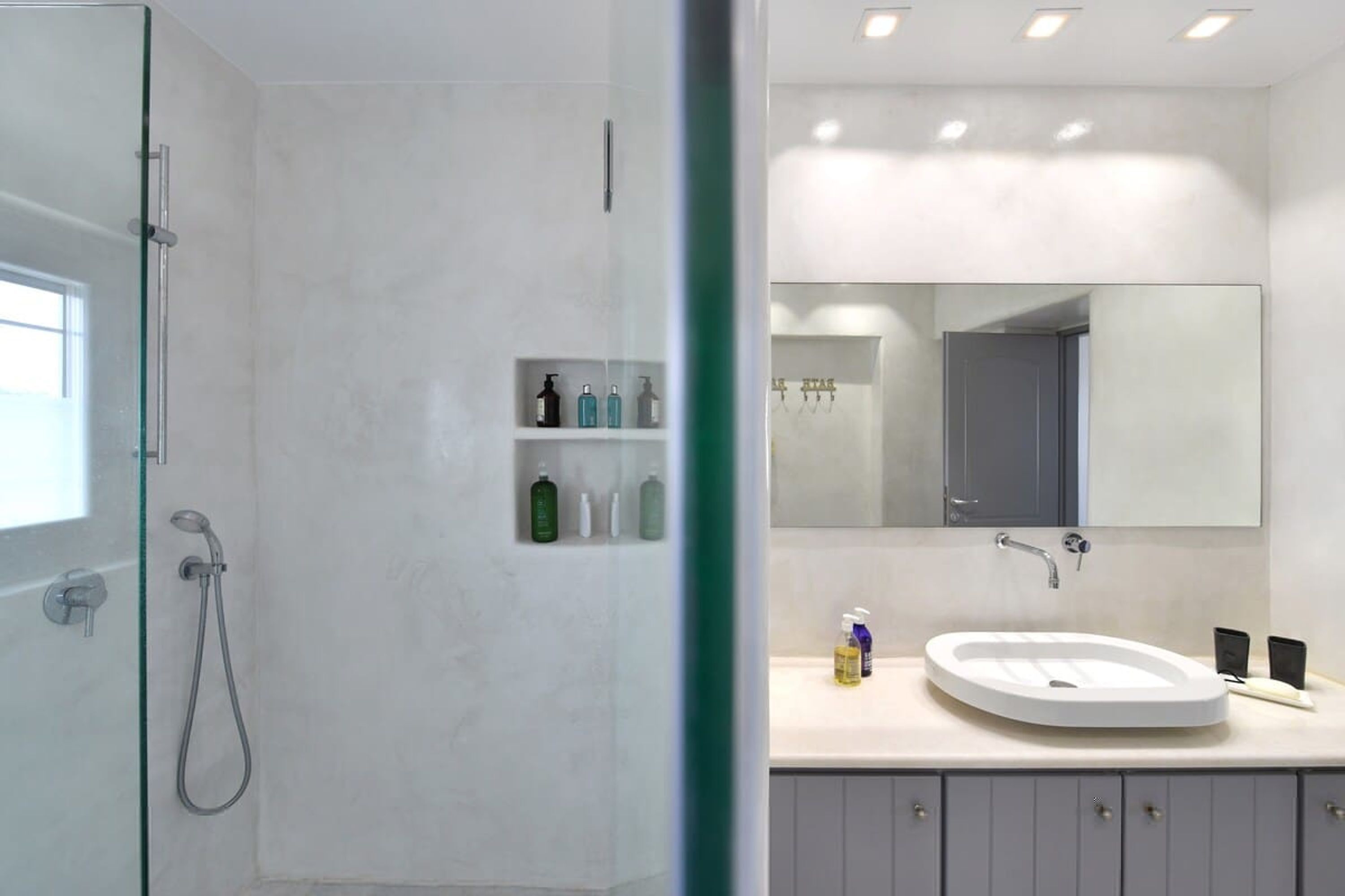 Un bany modern amb un cubicle de dutxa de vidre, un lavabo blanc i un gran mirall sobre el moble.