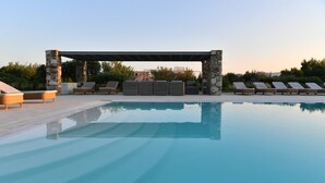 Ein Pool mit Liegestühlen und einer Steinstruktur.