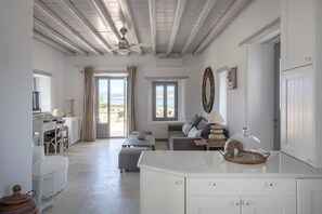 Un vaste espace de vie doté d’un ventilateur de plafond, d’un canapé, d’une table à manger et offrant une vue dégagée grâce à une grande fenêtre.