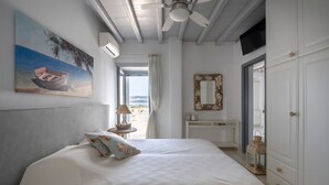 Ein Schlafzimmer mit Bett, Deckenventilator, Gemälde, Fenster und Kleiderschrank.