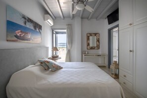 Une chambre à coucher avec un lit, un ventilateur de plafond, un tableau, une fenêtre et une armoire.
