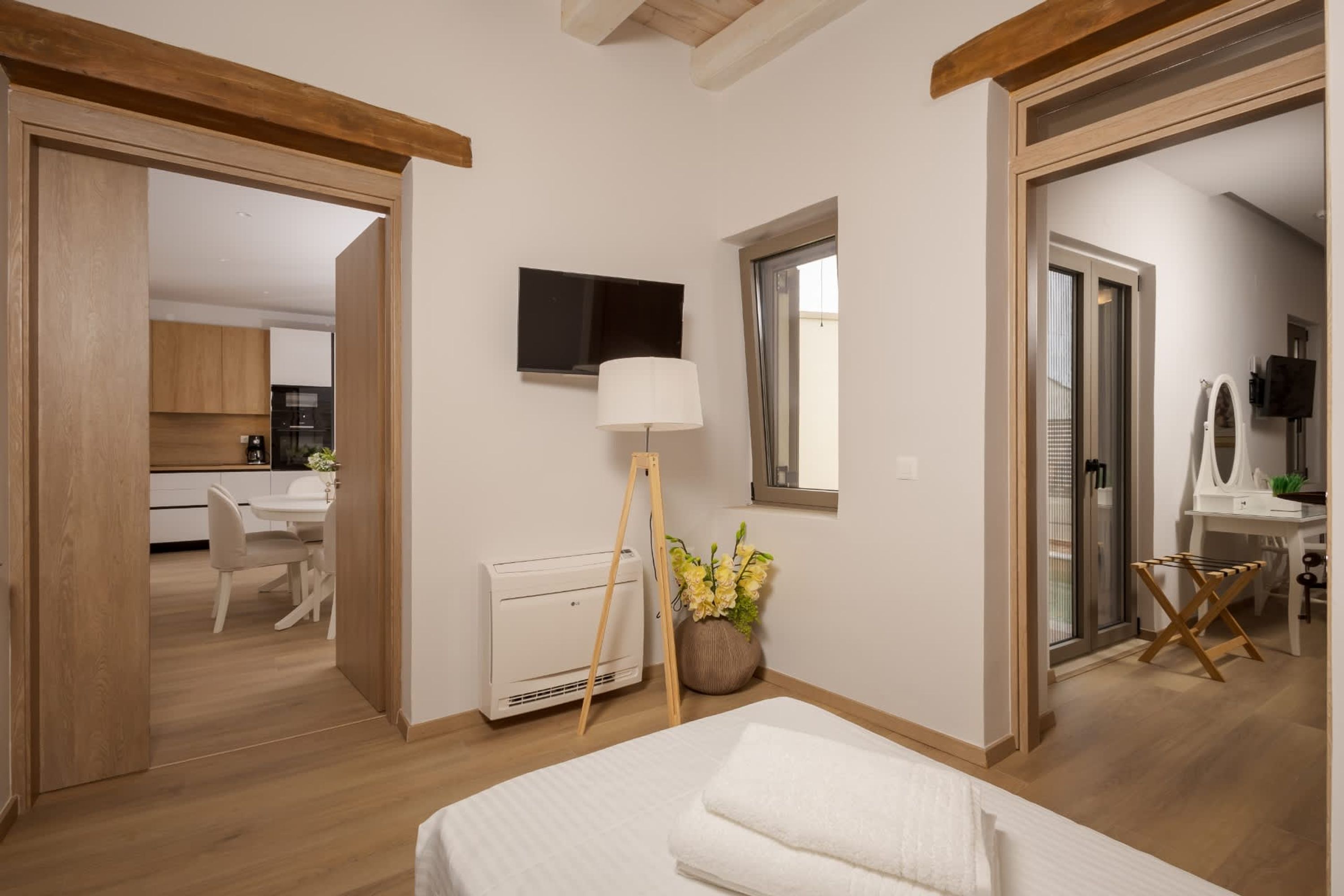 Ein Schlafzimmer mit Bett, Nachttisch, Lampe, einem Fenster und Blick auf eine Küche und einen Essbereich.