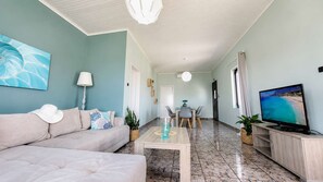 Una sala de estar con sofá, mesa de centro, televisor y comedor con sillas y mesa.