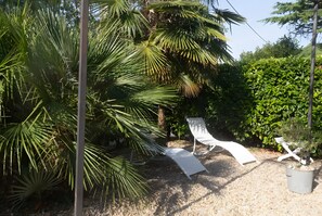 Ein Garten mit Palmen, einer weißen Liege und einem Blumentopf.