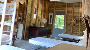 A rustic wooden room with a bunk bed, a desk, a mirror, a fan, and a window. - Holiday Home “Dormitory in Charente” with Private Terrace and Shared Garden (Jarnac)